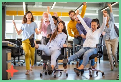 A team celebrating, rolling across an office on their chairs